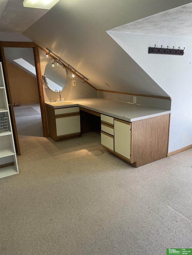 bonus room with sink, built in desk, light carpet, and vaulted ceiling