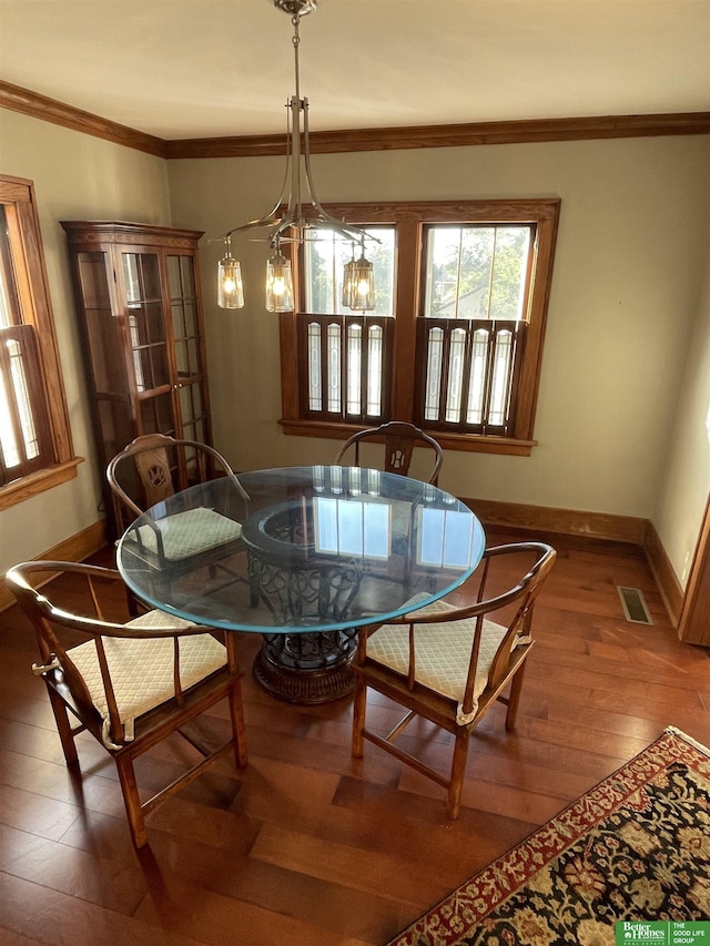 dining room featuring hardwood / wood-style floors, ornamental molding, and a notable chandelier