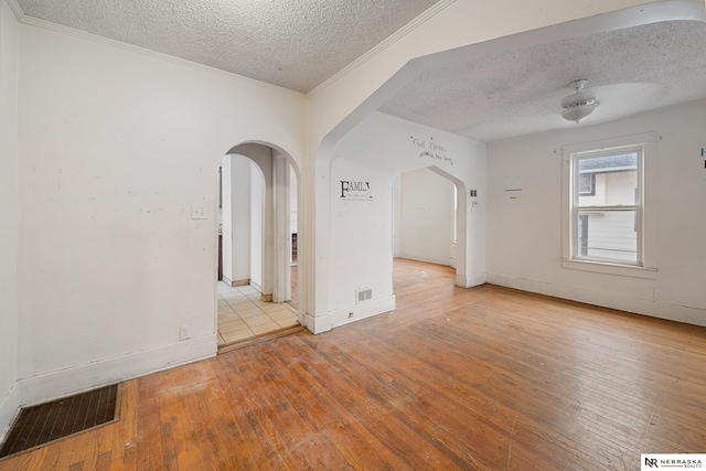 spare room with ceiling fan, crown molding, light hardwood / wood-style floors, and a textured ceiling