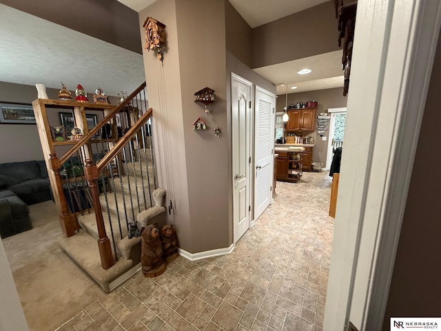 hall with stone finish flooring, stairway, recessed lighting, and baseboards