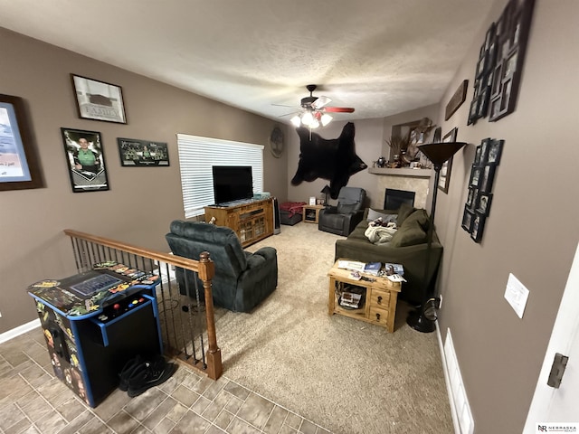 carpeted living room with a textured ceiling, baseboards, a ceiling fan, and a tile fireplace