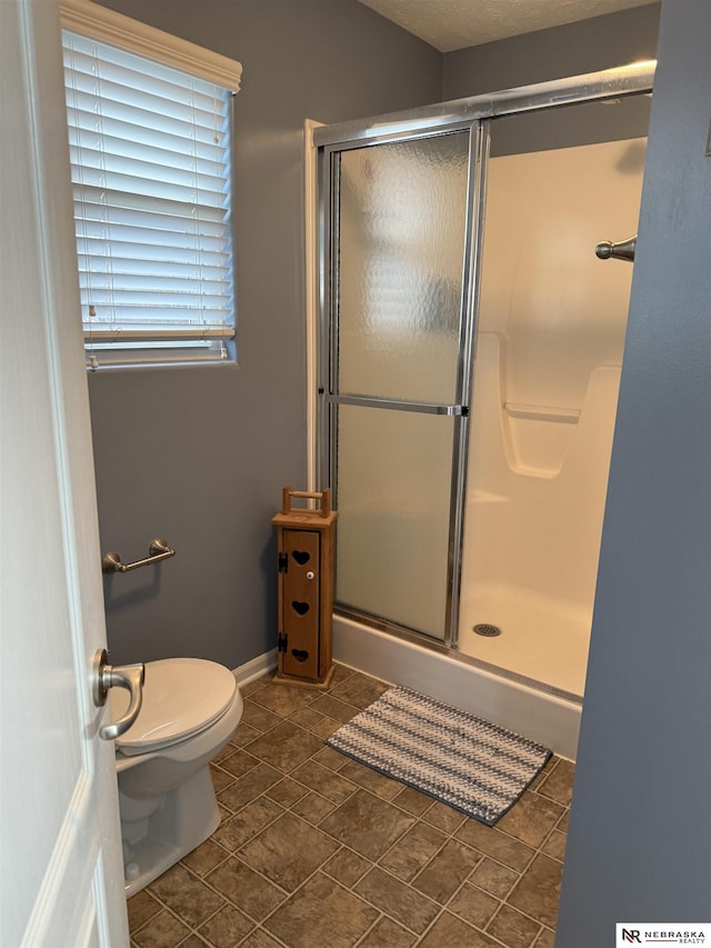 full bath with toilet, a shower stall, and baseboards