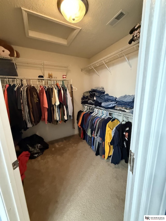 spacious closet featuring carpet floors, attic access, and visible vents