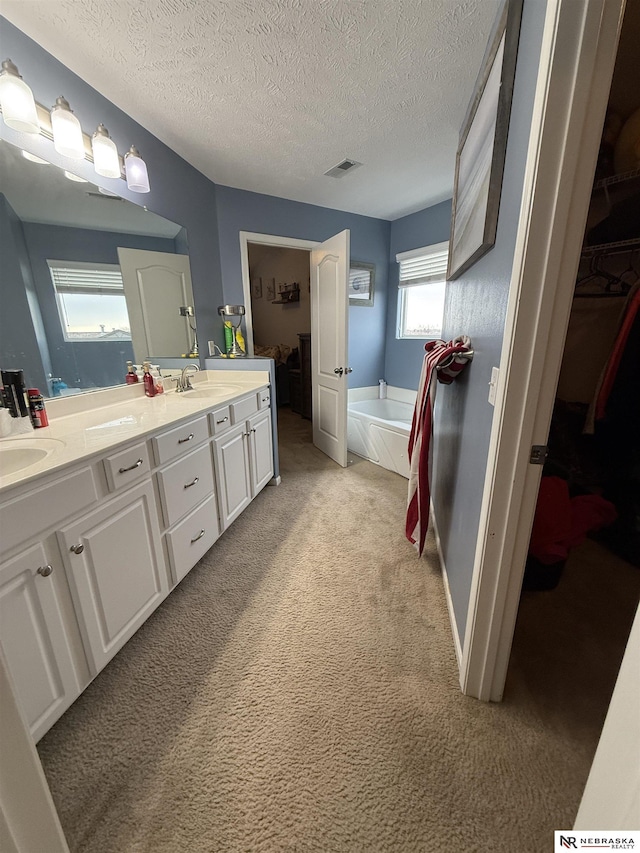 bathroom featuring a bath, double vanity, carpet, and visible vents