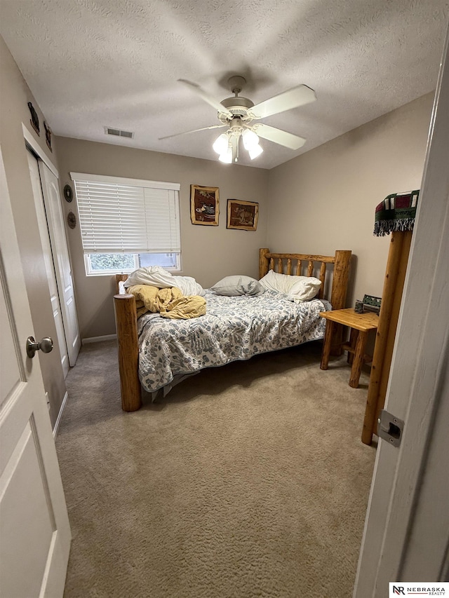 carpeted bedroom featuring ceiling fan, a textured ceiling, visible vents, baseboards, and a closet