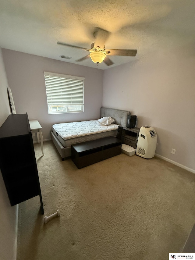 unfurnished bedroom featuring light carpet, baseboards, visible vents, a ceiling fan, and a textured ceiling