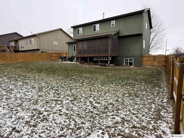 rear view of house with a fenced backyard and a sunroom