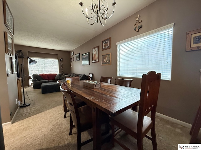 dining area featuring carpet floors, a chandelier, a textured ceiling, and baseboards