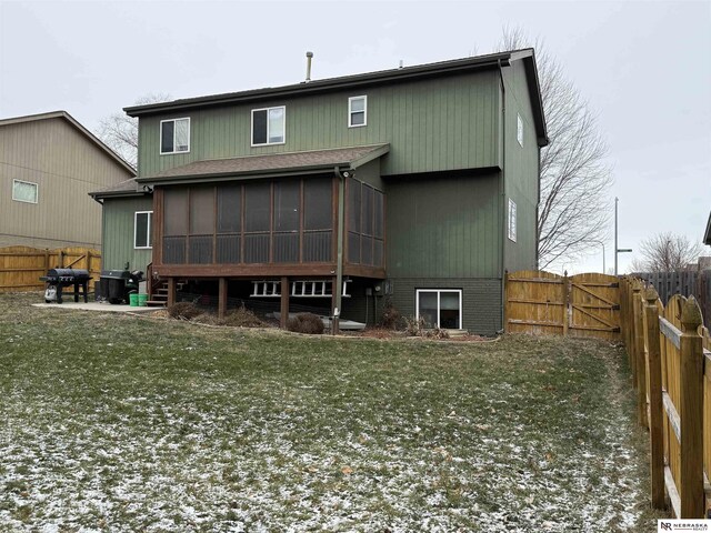 back of house featuring a lawn, a fenced backyard, and a sunroom