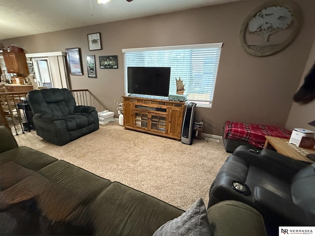 living area featuring light carpet, ceiling fan, and baseboards