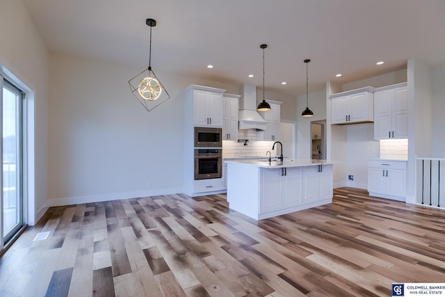 kitchen with white cabinetry, pendant lighting, stainless steel appliances, and custom range hood