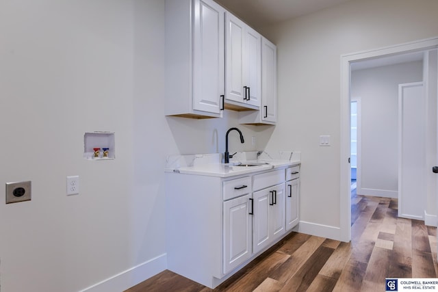 laundry area featuring electric dryer hookup, cabinets, sink, hookup for a washing machine, and dark hardwood / wood-style flooring