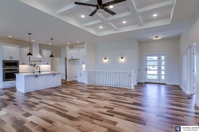 kitchen featuring white cabinetry, premium range hood, stainless steel appliances, and hanging light fixtures