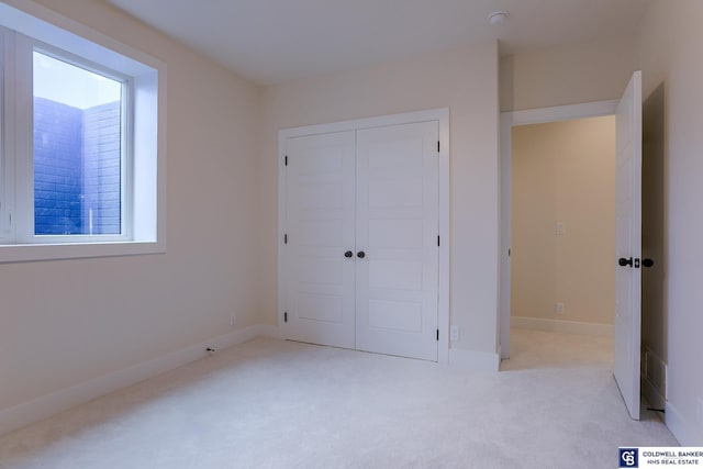 unfurnished bedroom with multiple windows, a closet, and light colored carpet