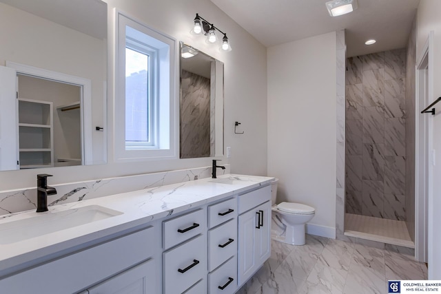 bathroom with a tile shower, vanity, and toilet