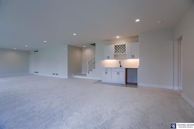 unfurnished living room with wet bar and light carpet