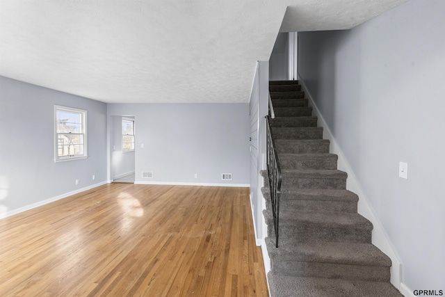 stairway featuring a textured ceiling and hardwood / wood-style flooring