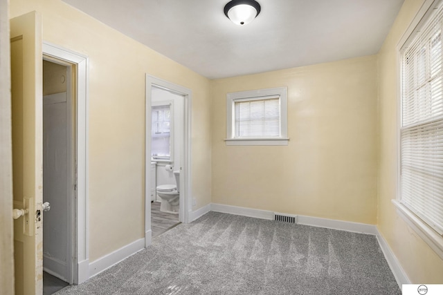 unfurnished bedroom featuring carpet floors and ensuite bath