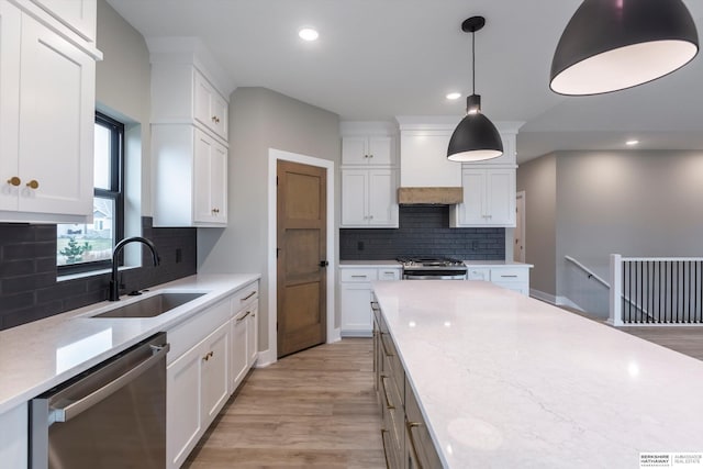 kitchen featuring premium range hood, white cabinets, sink, light stone countertops, and stainless steel appliances