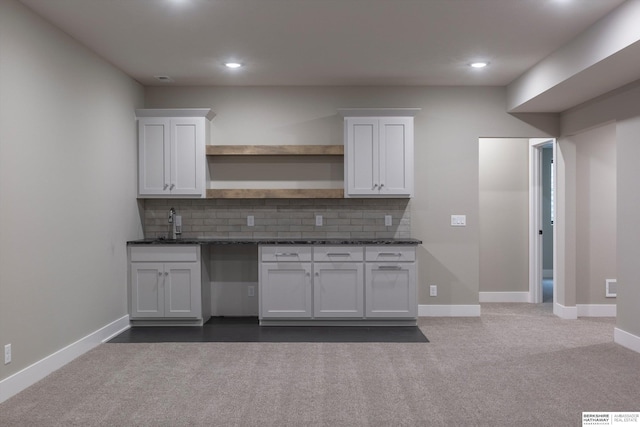 kitchen featuring sink, dark stone countertops, white cabinetry, and backsplash