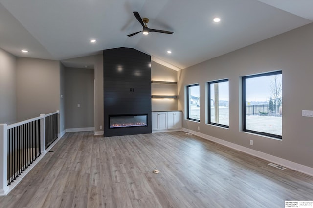 unfurnished living room with ceiling fan, a fireplace, lofted ceiling, and light wood-type flooring