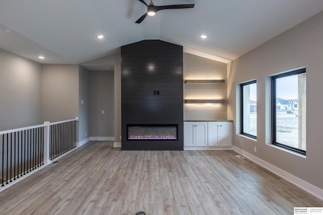 unfurnished living room with ceiling fan, a large fireplace, lofted ceiling, and light hardwood / wood-style flooring