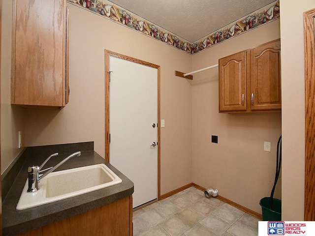 washroom featuring cabinets, a textured ceiling, electric dryer hookup, and sink