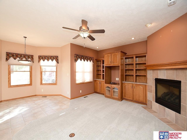 unfurnished living room with light carpet, ceiling fan, and a tiled fireplace