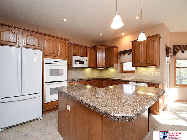 kitchen featuring white appliances, sink, light tile patterned floors, decorative light fixtures, and a kitchen island