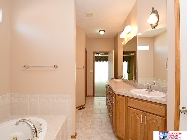 bathroom with tile patterned floors, vanity, and a relaxing tiled tub