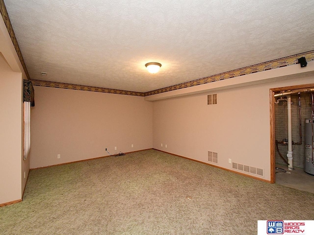 carpeted empty room featuring water heater and a textured ceiling