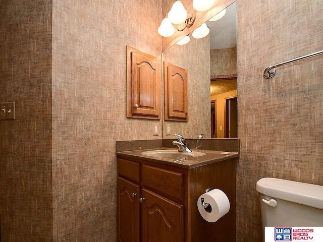 bathroom with vanity, an inviting chandelier, and toilet