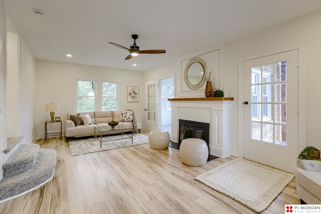 living room with ceiling fan, light hardwood / wood-style flooring, and a brick fireplace