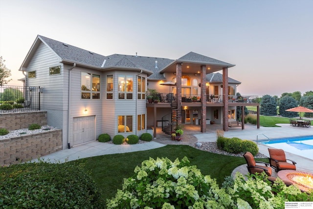 back house at dusk with a lawn, a swimming pool side deck, a patio, and a garage