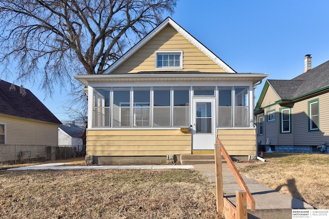 bungalow with a front lawn and a sunroom