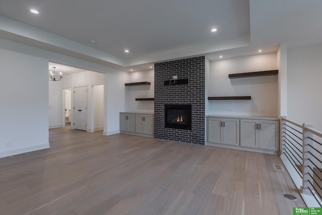 unfurnished living room with light wood-style flooring, recessed lighting, visible vents, baseboards, and a tiled fireplace