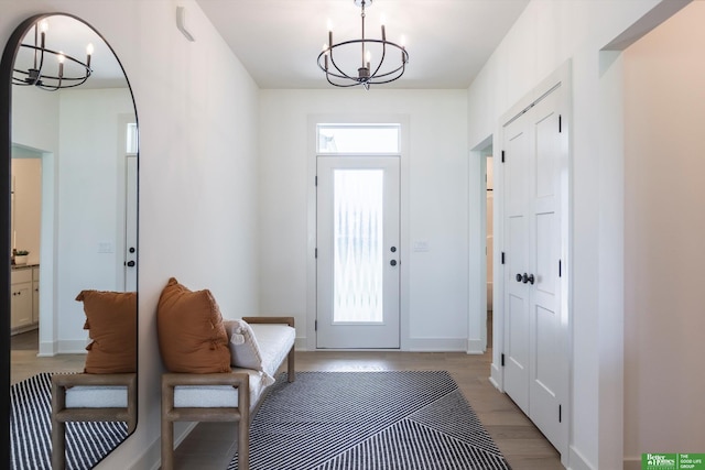 interior space with baseboards, a notable chandelier, and light wood finished floors