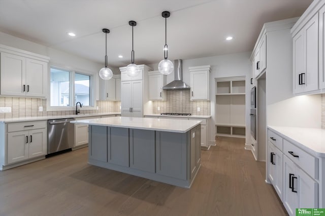 kitchen with a center island, light countertops, appliances with stainless steel finishes, wall chimney range hood, and wood finished floors