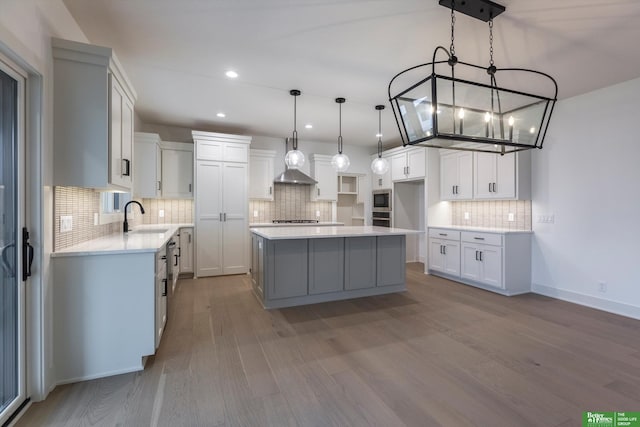 kitchen with a kitchen island, white cabinets, a sink, and wood finished floors