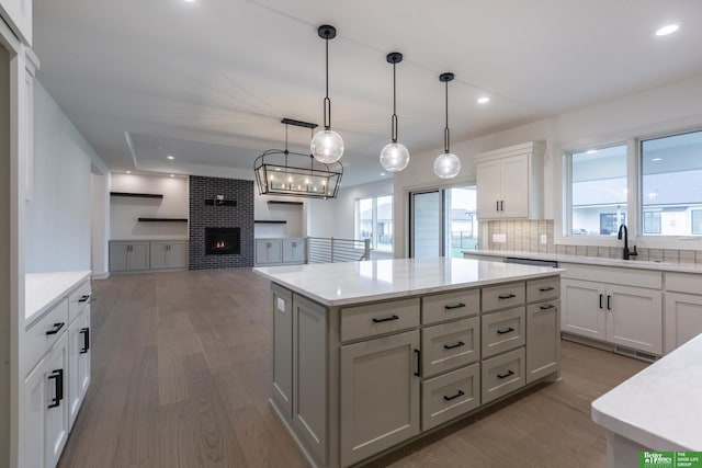 kitchen with dark hardwood / wood-style flooring, sink, pendant lighting, a fireplace, and a center island