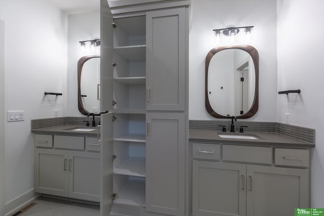 full bath with two vanities, a sink, visible vents, and baseboards