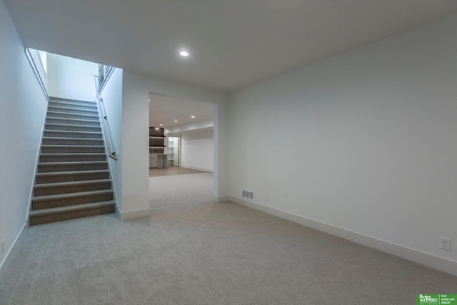 unfurnished living room featuring visible vents, baseboards, light colored carpet, stairway, and recessed lighting