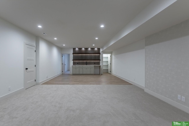 unfurnished living room with light wood finished floors, baseboards, light colored carpet, and recessed lighting