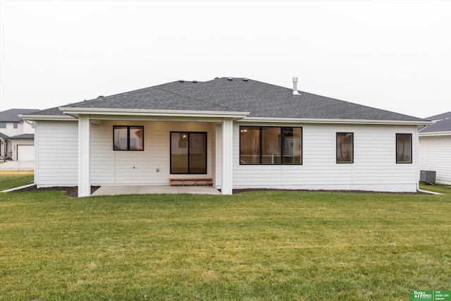 back of house featuring roof with shingles, cooling unit, a lawn, and a patio