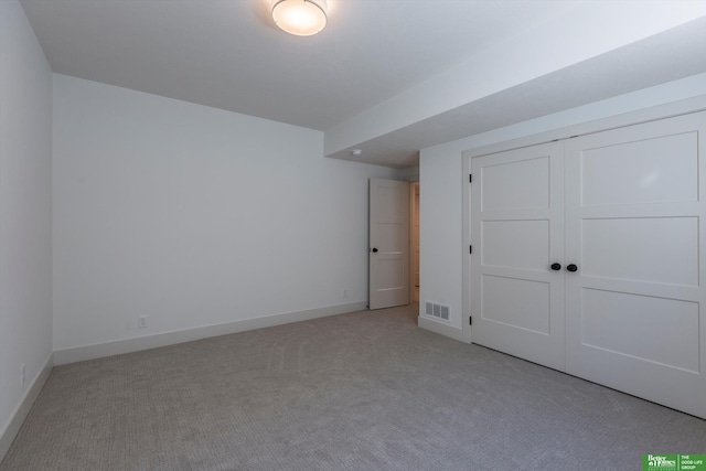 unfurnished bedroom with a closet, light colored carpet, visible vents, and baseboards