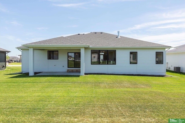 back of house with central air condition unit, a patio area, a shingled roof, and a lawn