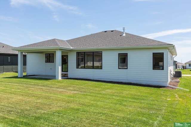 back of house with roof with shingles, a lawn, and central air condition unit