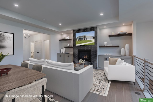 living room with a chandelier, light hardwood / wood-style flooring, and a brick fireplace