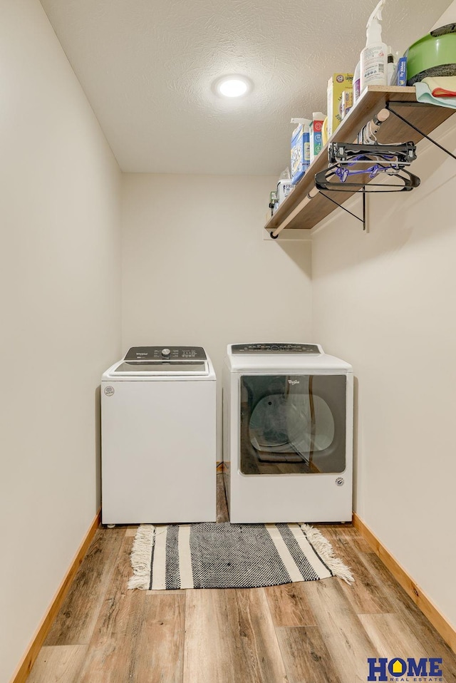 washroom with a textured ceiling, light wood-type flooring, and washer and clothes dryer