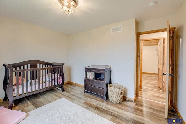 bedroom featuring a crib and light hardwood / wood-style floors